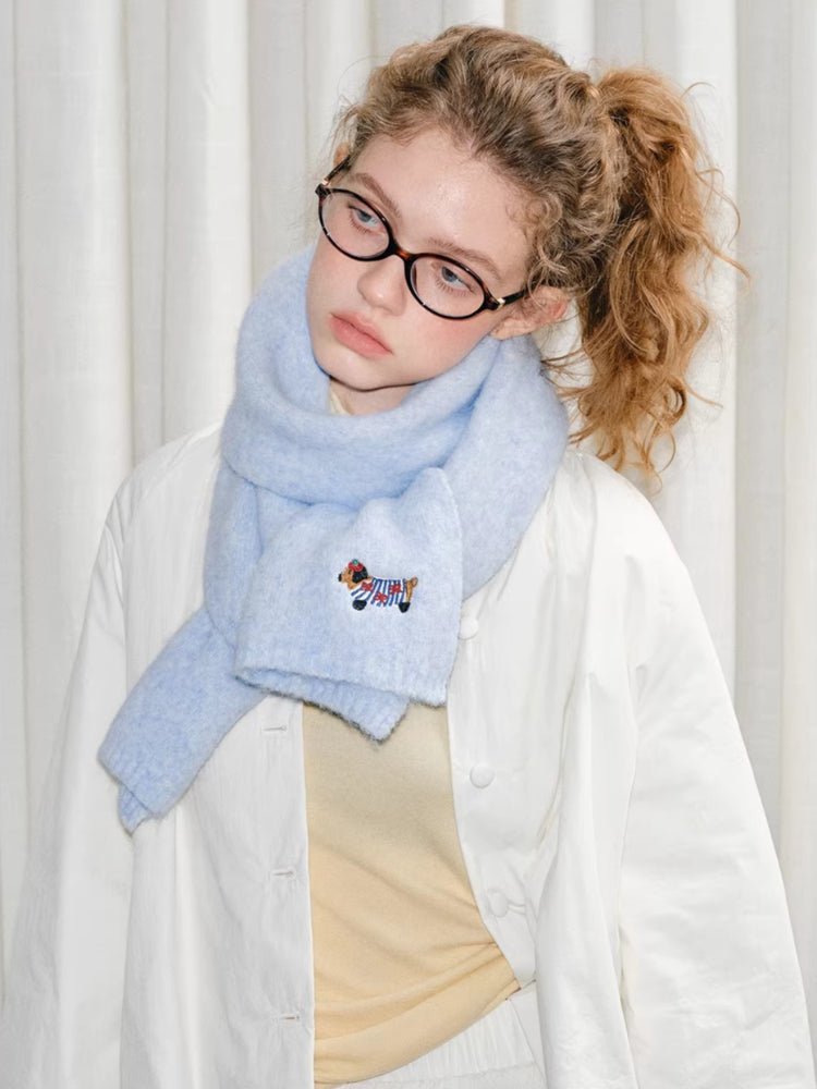 Front view of a woman accessorized with a soft, light blue winter scarf.