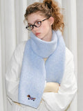 Detail shot of a sky blue scarf with an embroidered dog motif.