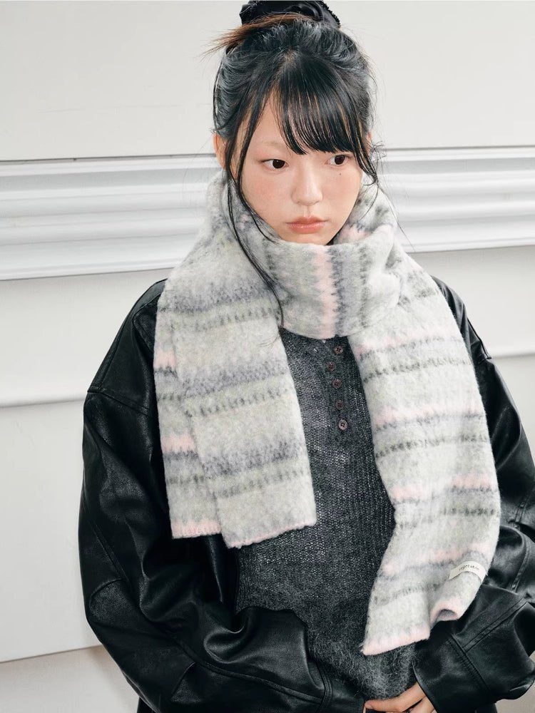 A young person wearing a light grey and pink striped knit scarf.