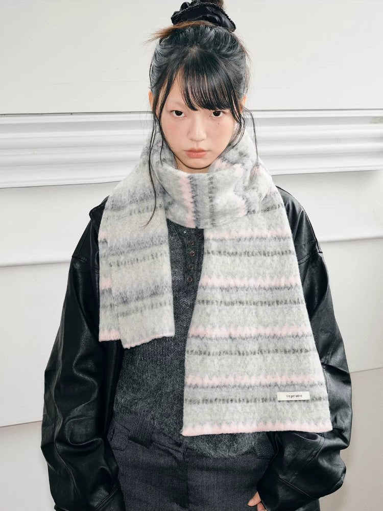 A young person models a light grey and pink striped knit scarf with a black jacket.