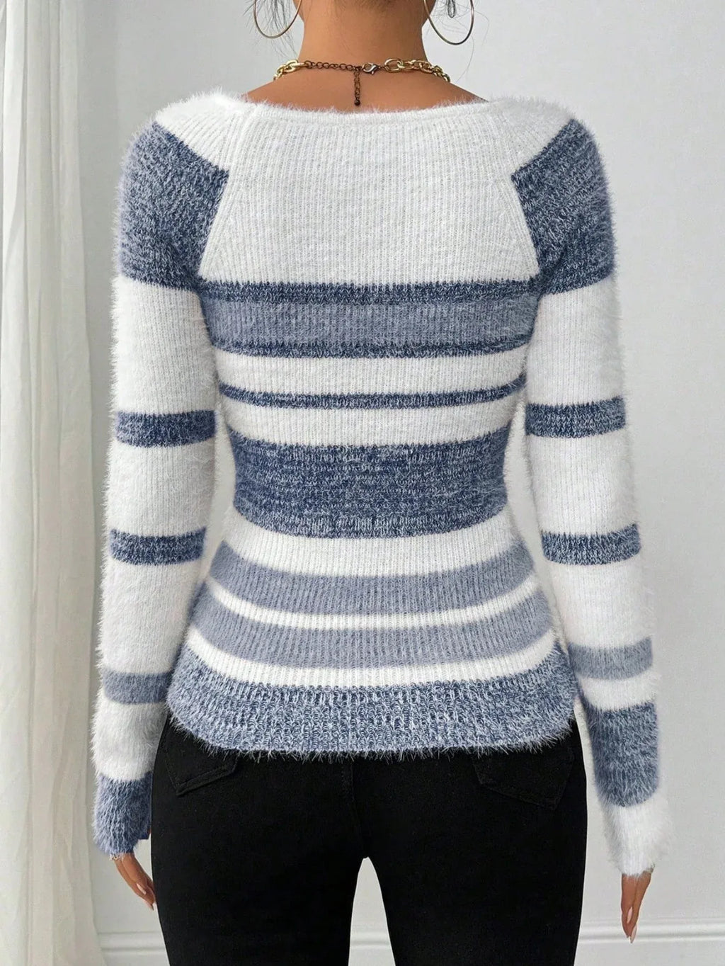 Back view of a woman in a blue and white striped fuzzy knit sweater.