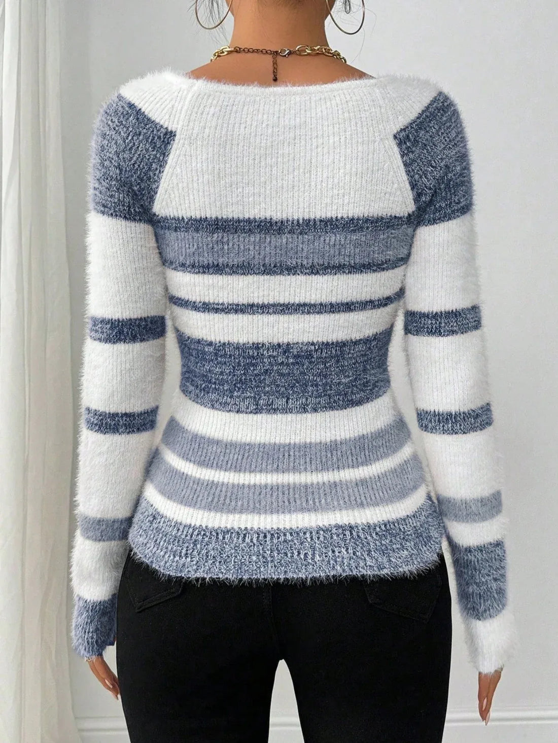 Woman wearing a blue and white striped fuzzy knit long sleeve top with a scoop neckline.