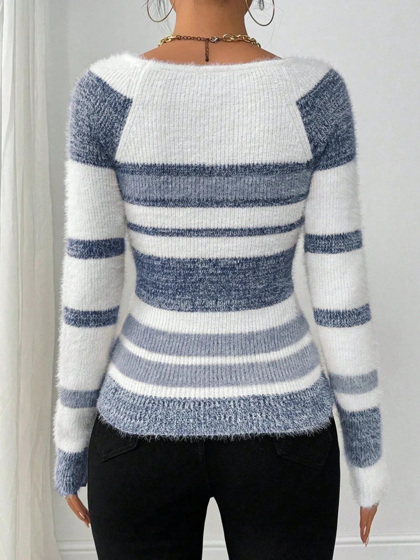 Back view of a woman in a blue and white striped fuzzy knit sweater.