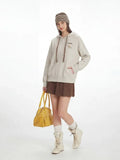 Full body shot of a model in a casual outfit featuring a hooded sweatshirt and skirt.