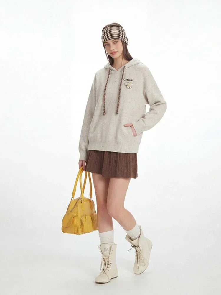 Full body shot of a model in a casual outfit featuring a hooded sweatshirt and skirt.
