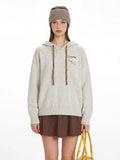 Front view of a woman in a speckled knit hoodie, showcasing the drawstring and pocket detail.