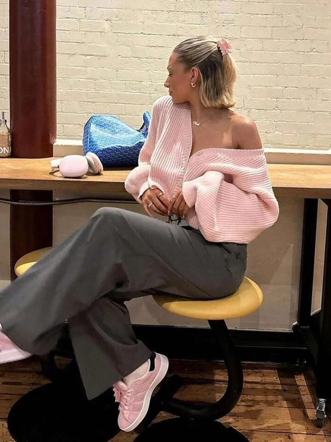 Woman wearing a pink knit cardigan with button front closure and balloon sleeves.