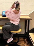 Rear view of a woman wearing a pink knit cardigan.