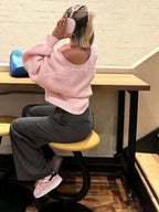 Rear view of a woman wearing a pink knit cardigan.