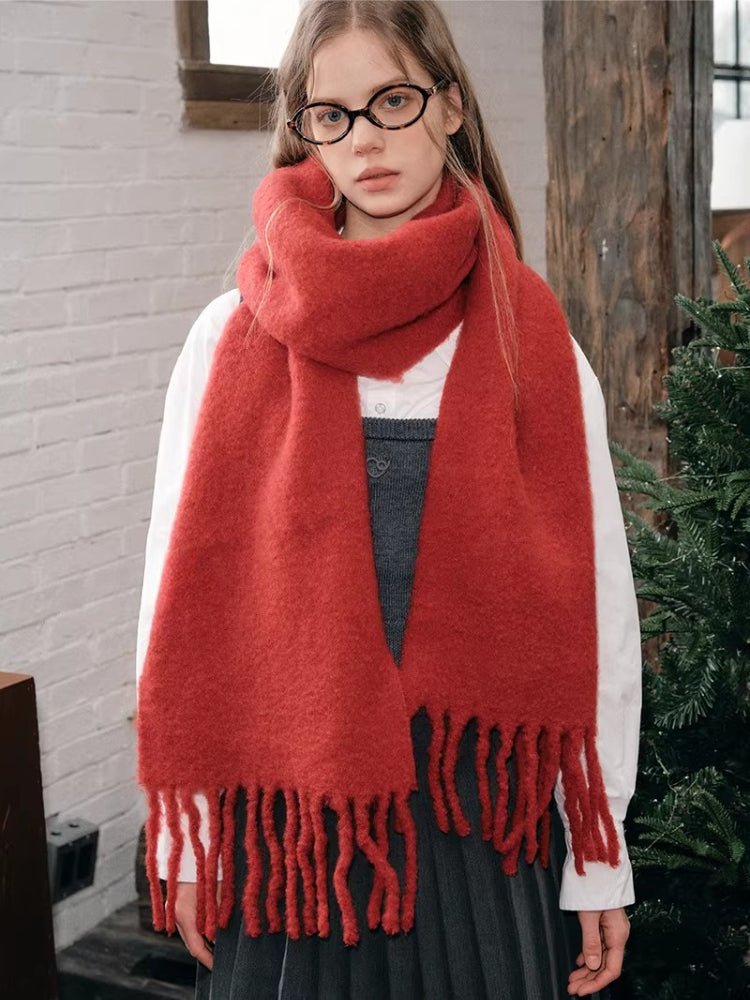 Woman wearing a red textured knit scarf with fringe trim.