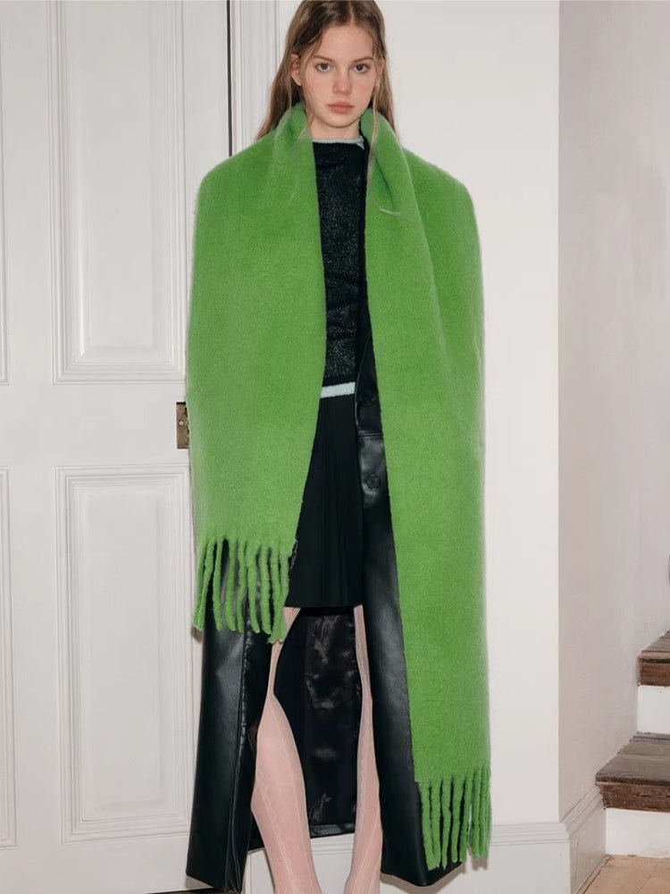 Full-body view of a woman wearing a long green scarf with fringe.