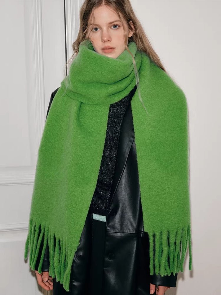 Woman wearing a bright green textured knit scarf with fringe trim.