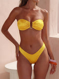 Woman wearing a bright yellow strapless bikini with ruched detail and gold hardware