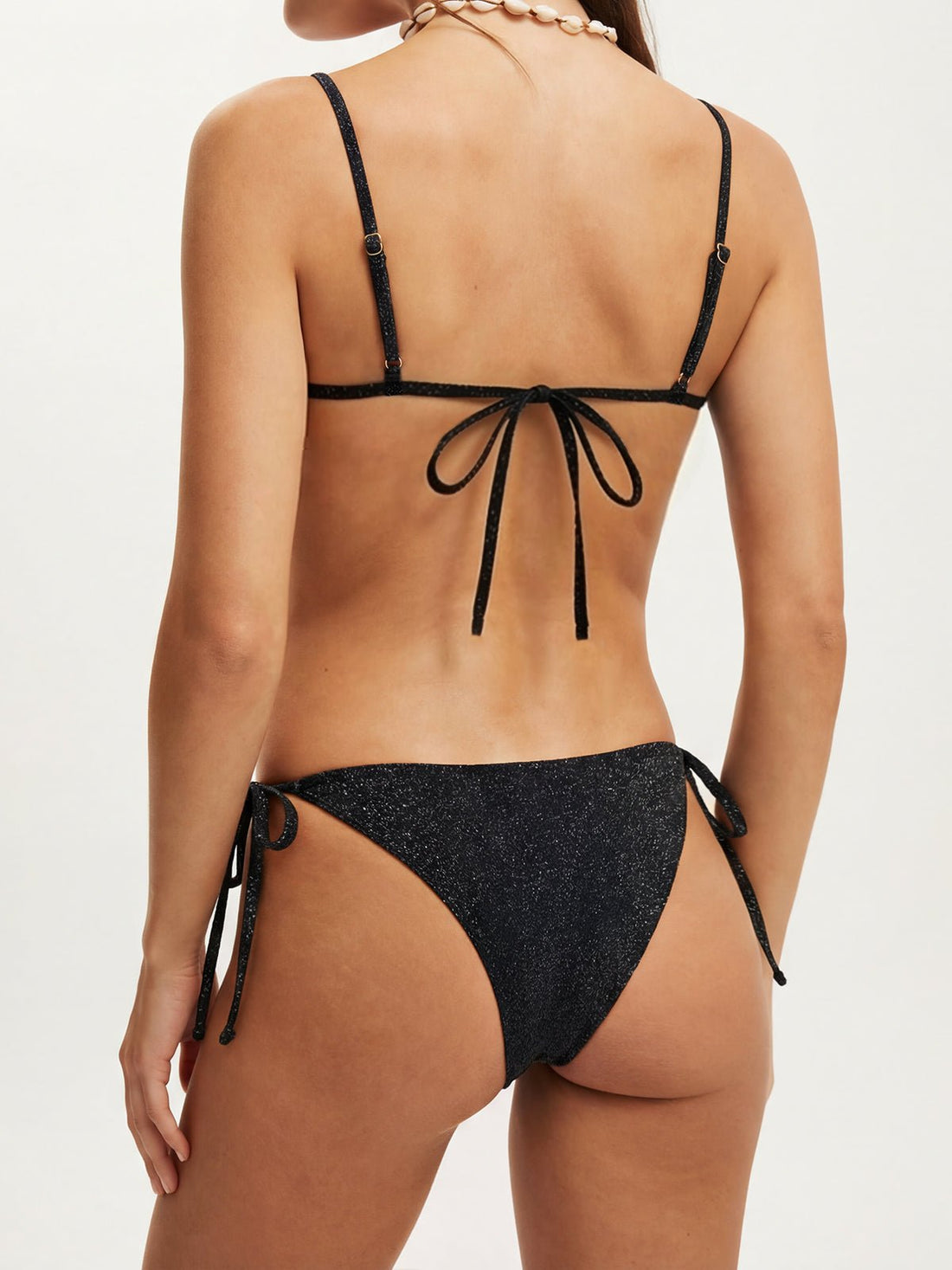 Woman wearing a black sparkly bikini with a shell detail at the bust