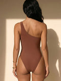 Back view of a woman wearing a brown one-shoulder one-piece swimsuit.