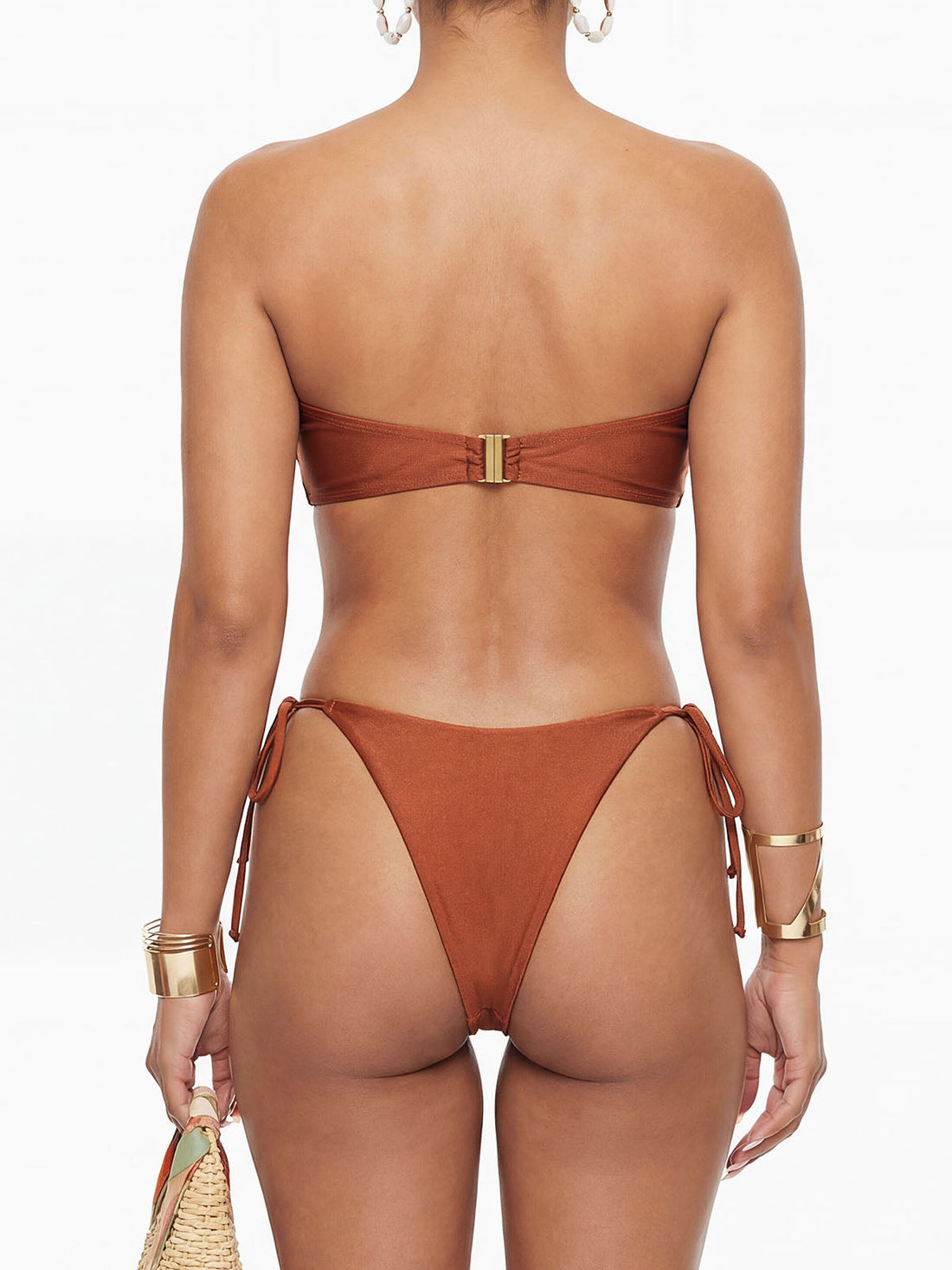 Woman wearing a rust-colored strapless bikini with ruched detailing and a gold O-ring in the front.