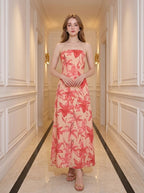 Woman wearing a strapless peach maxi dress with a large red floral print, standing in a hallway.