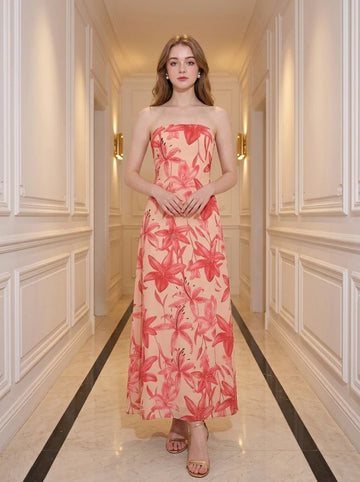Woman wearing a strapless peach maxi dress with a large red floral print, standing in a hallway.