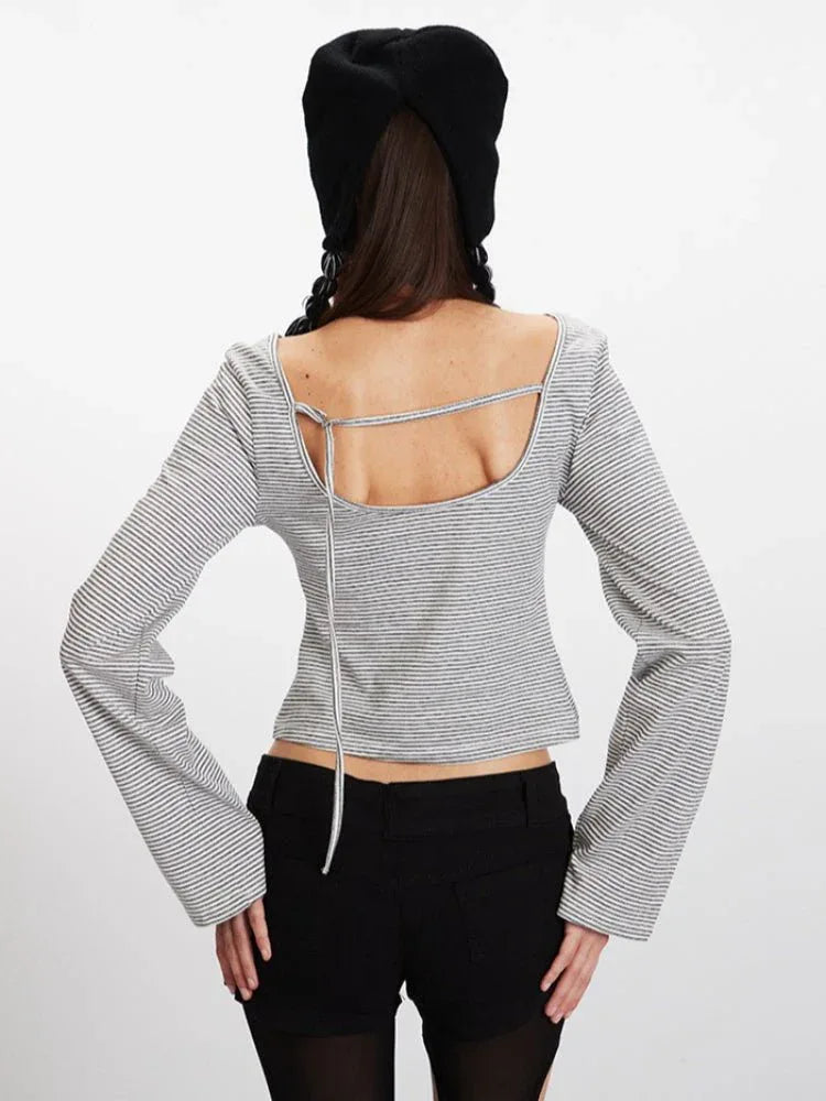 Model wearing a grey and white striped long-sleeve cropped top with bell sleeves and black shorts