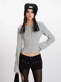 Front view of a woman in a striped long-sleeve cropped top, black shorts, and striped thigh-high socks