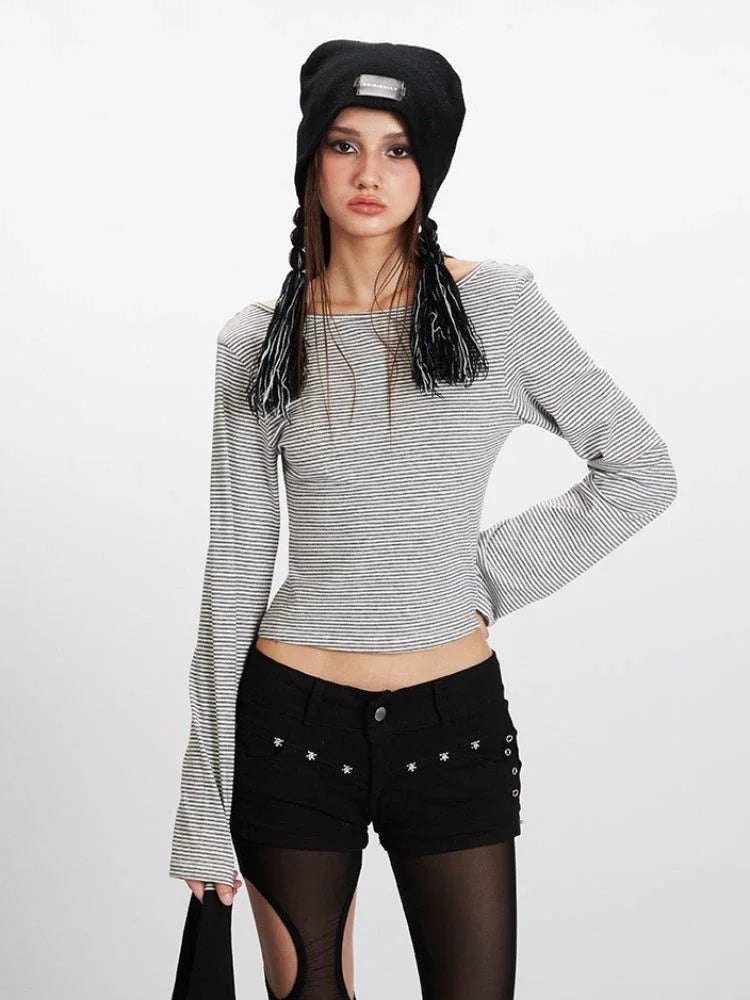 Front view of a woman in a striped long-sleeve cropped top, black shorts, and striped thigh-high socks