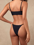 Back view of a woman wearing a black bikini set on a textured background