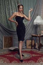 Woman posing in a black ruched sheath dress with spaghetti straps.