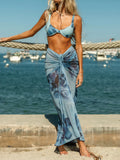 Woman wearing a blue floral print bikini top and a matching sheer maxi skirt with a tie waist.