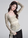 Model showcasing a long-sleeve sheer top with a subtle print and a contrasting band around the midsection.