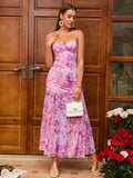 Full body shot of a woman in a pink floral print maxi dress with a handbag.