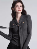 Close-up of a dark grey ribbed knit top featuring a tie-neck and decorative gold buttons.
