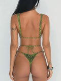 Back view of a woman in a green printed one-piece swimsuit with thin straps and a thong bottom, highlighting the adjustable tie closure.