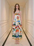 Woman wearing a white midi dress with a tropical print, standing in a hallway.