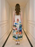 Back view of a woman wearing a white midi dress with a tropical print, standing in a hallway.