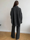 Woman wearing a charcoal knit turtleneck sweater and wide leg pants from the back