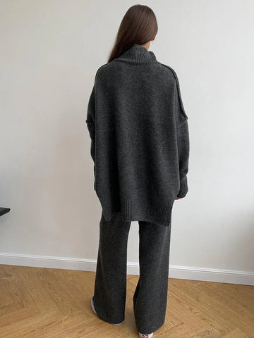 Woman wearing a charcoal knit turtleneck sweater and wide leg pants from the back
