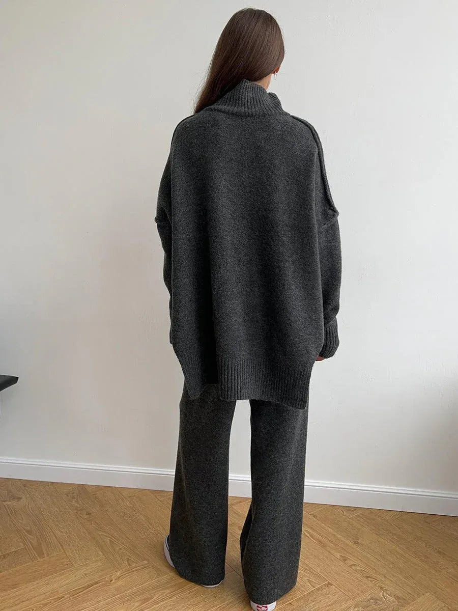 Woman wearing a charcoal knit turtleneck sweater and wide leg pants from the back