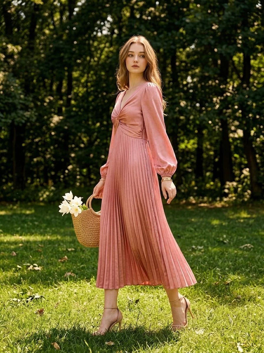 Woman wearing a pink satin midi dress with a twisted knot bodice and pleated skirt, walking in a park.