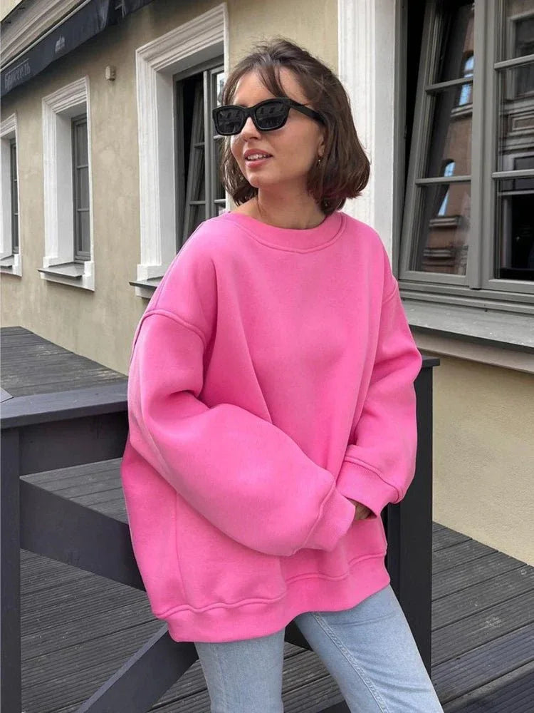 Woman wearing a bright pink oversized sweatshirt with light wash jeans.