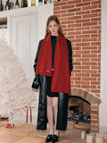 Full body shot of a woman wearing a red scarf over a black jacket and dress.