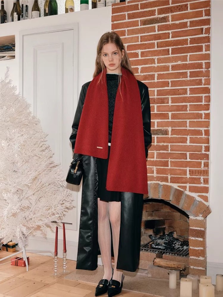 Full body shot of a woman wearing a red scarf over a black jacket and dress.