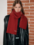 Close-up of a woman's neck and shoulders showing a red ribbed knit scarf.