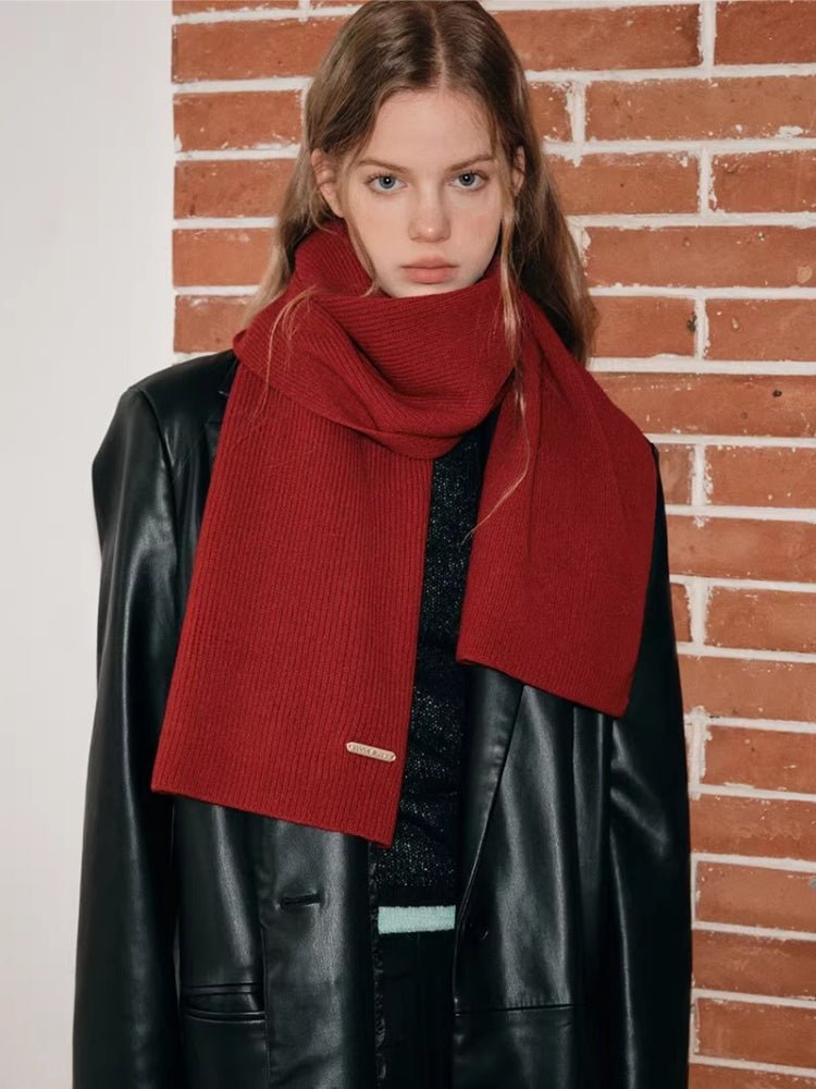 Close-up of a woman's neck and shoulders showing a red ribbed knit scarf.