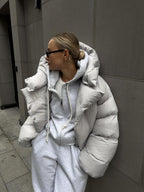 Side profile of a woman wearing a light grey hooded puffer jacket.