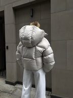 Back view of a woman in a light grey oversized puffer jacket with a large hood.