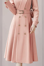 detail shot of the skirt of a pink midi coat dress with a full, flared silhouette and double-breasted button detailing