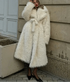 Woman standing in a long white faux fur coat with a belted waist