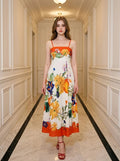 Woman wearing a white midi dress with a bold floral print and orange trim, standing in a hallway.