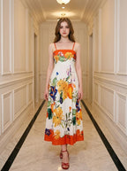 Woman wearing a white midi dress with a bold floral print and orange trim, standing in a hallway.