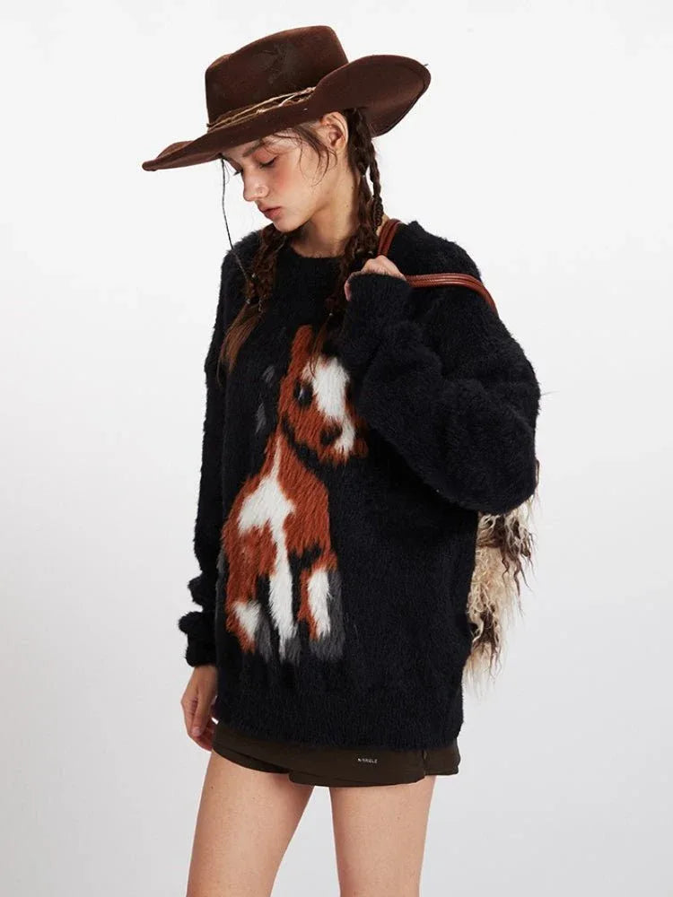 Close-up profile of a woman wearing a black fuzzy knit sweater with a brown and white horse graphic, brown cowboy hat, and brown boots.